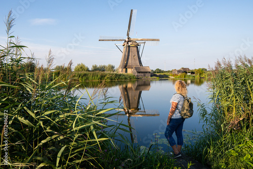 Woman enjoying the view of traditional Dutch windmill in Kinderdijk village located in South Holland province, the Netherlands
