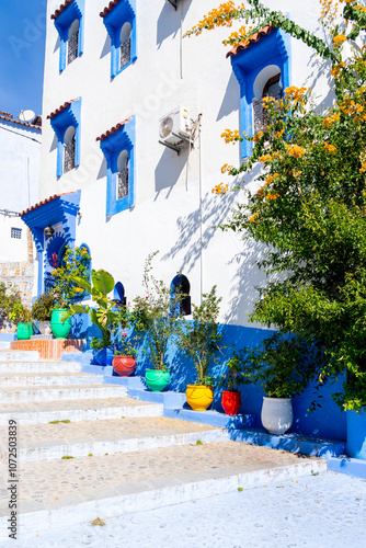 Blue colored houses and streets decorated with colorful flower pots in Chefchaouen, Morocco. Chefchaouen is a small city referred to as the “blue city” 
