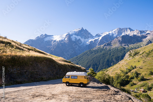 Retro camper van parked on the roadside with high mountains in the background, Ecrins National Park, France