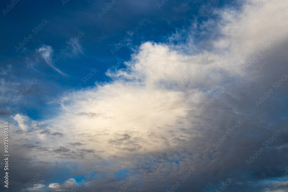 Obraz premium a white cloud lit by the evening sun in a dark blue sky