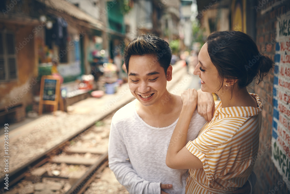 City, railway and couple with love on vacation, travel adventure and exploring for anniversary. Interracial marriage, woman and man with smile for admiration, loyalty and bonding outdoor in Vietnam City, railway and couple with love on vacation, travel adventure and exploring for anniversary. Interracial marriage, woman and man with smile for admiration, loyalty and bonding outdoor in Vietnam