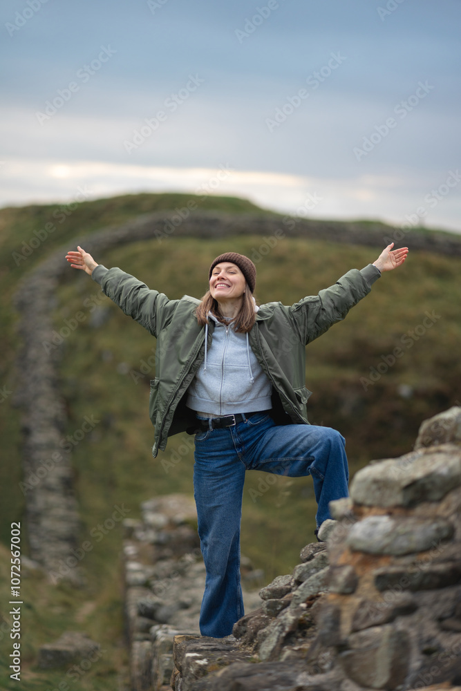 Woman tourist with Hadrian's wall on the background, happy Traveler travel Northumberland, United Kingdom. Destination and Vacation Woman tourist with Hadrian's wall on the background, happy Traveler travel Northumberland, United Kingdom. Destination and Vacation