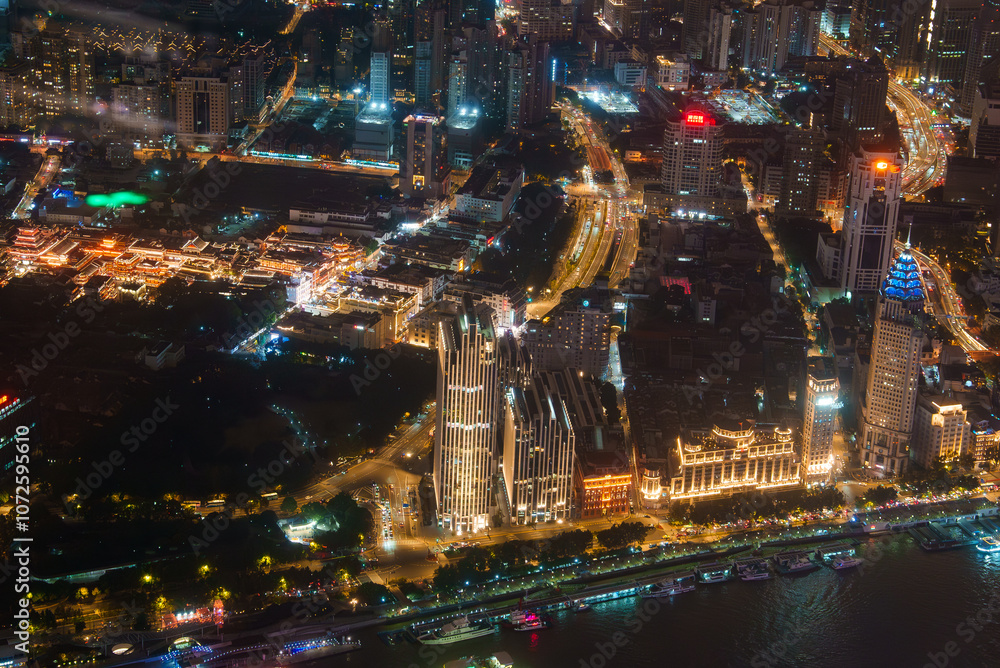 Fototapeta premium Aerial view of Shanghai at night, featuring the illuminated Bund, modern skyscrapers, and traditional architecture of the old town along the Huangpu River.