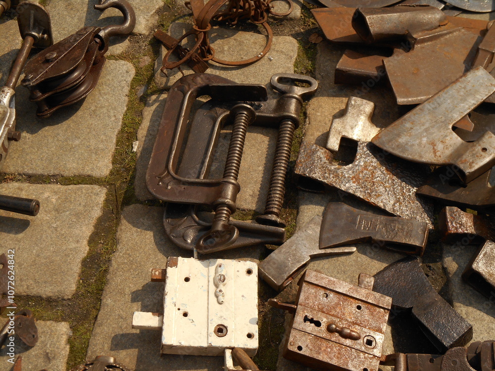 Old metal objects and tools lying on the pavement. Antiques market, Świdnica, Poland.