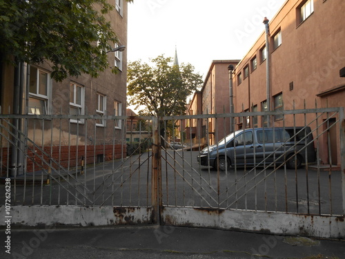 Old buildings, yard behind a locked metal gate
