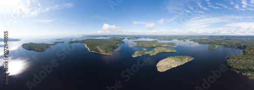 Aerial top view to island Kilpola overgrown with sparse trees in summer sunny day. Skerries Ladoga lake consisting of 650 rocky islands and steep cliffs. National park, Karelia, Russian nature.