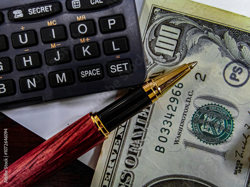 US Dollar money notes, pen and calculator on the table with narrow focus photo