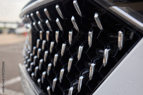 A detailed view of a contemporary car front grille with a stylish design and headlights