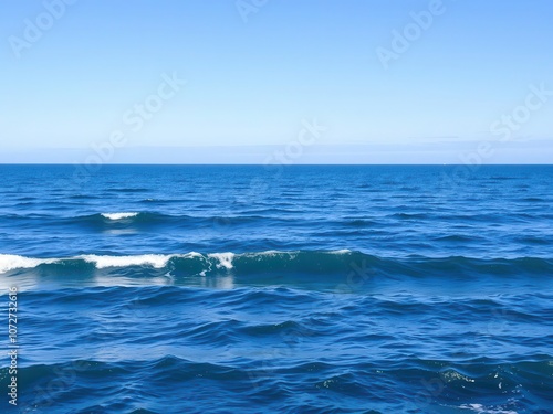 A serene ocean background with gentle waves rolling towards the shore under a clear blue sky, beach, horizon, vacation