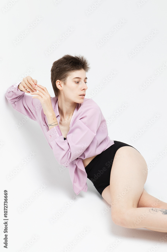Stylish woman model with short haircut in pink shirt posing on white background. Stylish woman model with short haircut in pink shirt posing on white background.