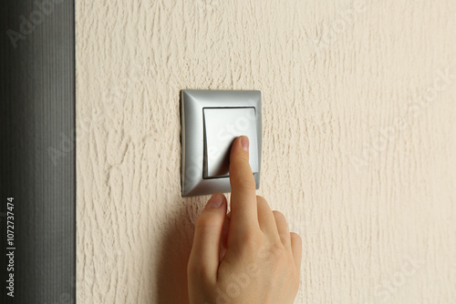 Woman turning light switch on, closeup view