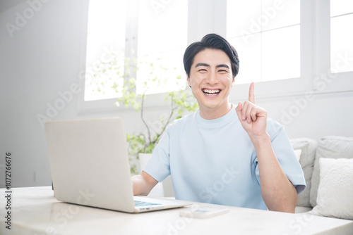 Tablou pe pânză Smiling young man using a computer in a brightly lit room Pointing with a fresh