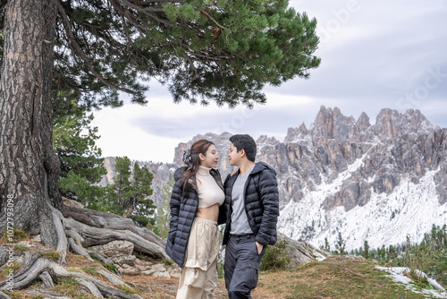 Couple under the tree enjoy the view of alpine mountain landscape snowy.