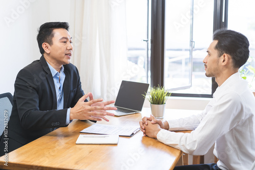 Asian young manager, employer man interview with person, have question about resume and listen to candidate answer, conversation together at office. Recruitment employee job concept.