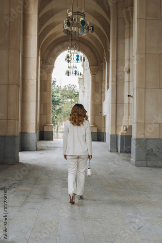 Woman White Suit Walking Arched Corridor Building Entrance