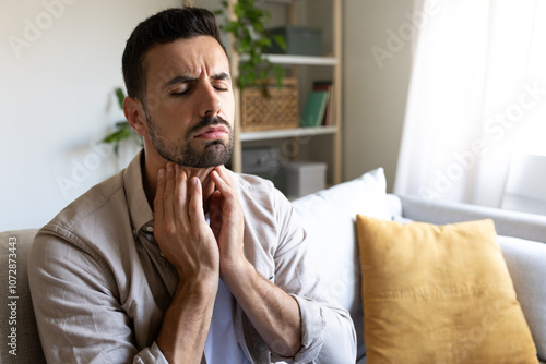 Bilde på lerret Man suffering from sore throat touching neck feeling pain