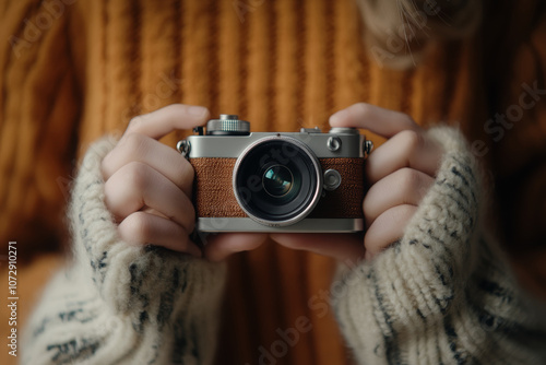 A person in a warm sweater holds a vintage camera, capturing memories in a cozy setting