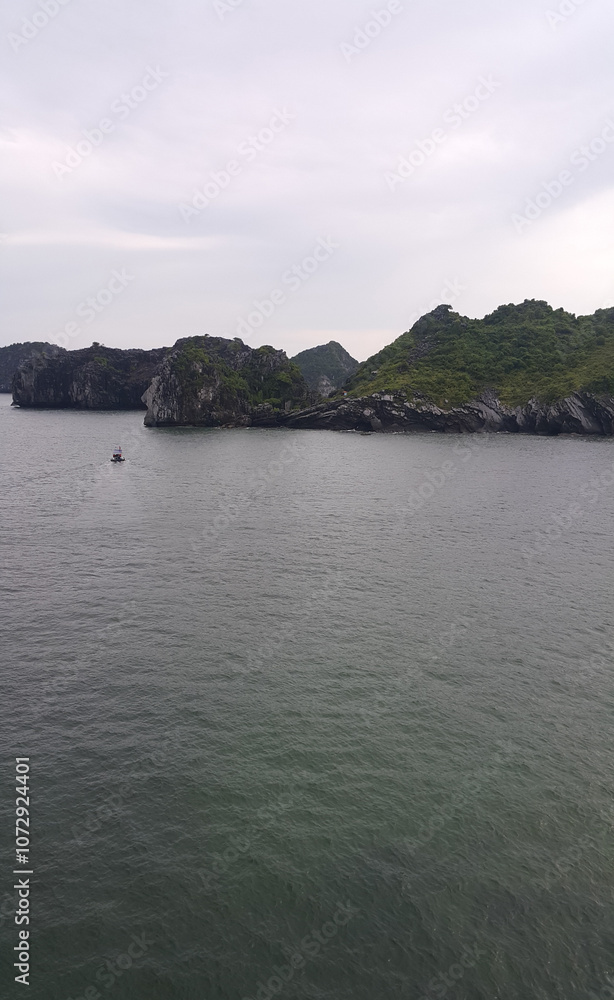 Scenic view of rocky islands in calm waters during overcast weather Scenic view of rocky islands in calm waters during overcast weather
