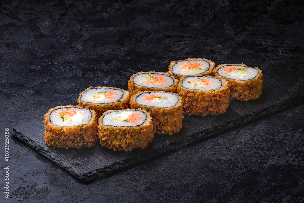 Japanese rolls, sushi fried tempura salmon and cream cheese on black background. Japanese rolls, sushi fried tempura salmon and cream cheese on black background.