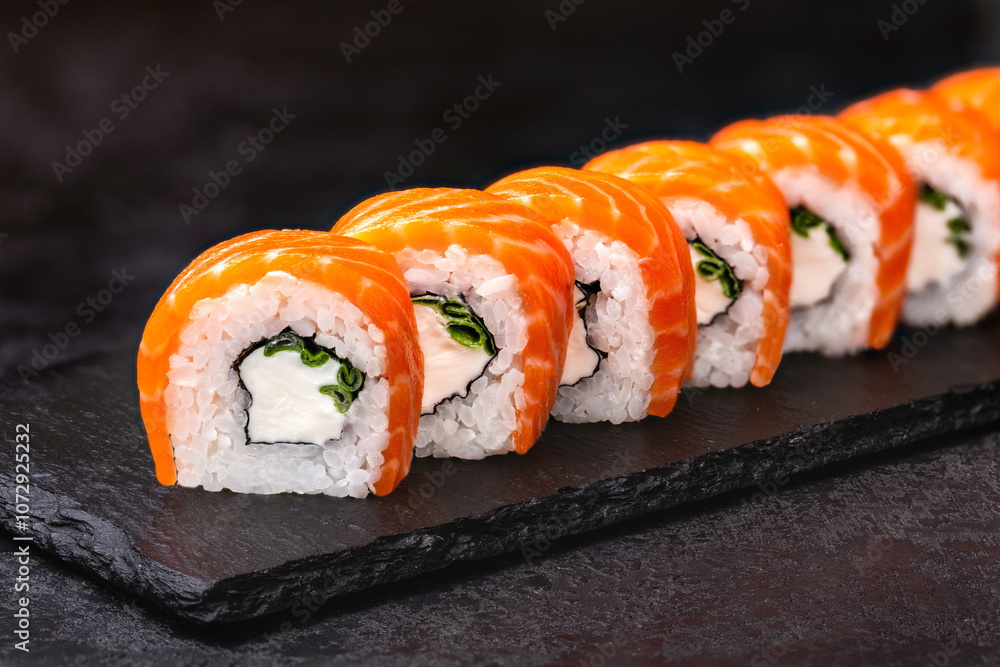 Japanese rolls, Philadelphia sushi with salmon and cream cheese on a black background. Japanese rolls, Philadelphia sushi with salmon and cream cheese on a black background.