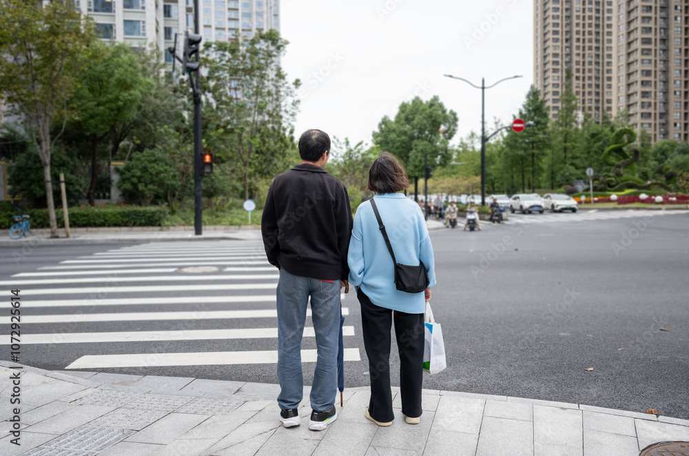 People stop at red lights on pedestrian crossing. Unrecognizable cars and motorbikes in the distance. Shanghai.