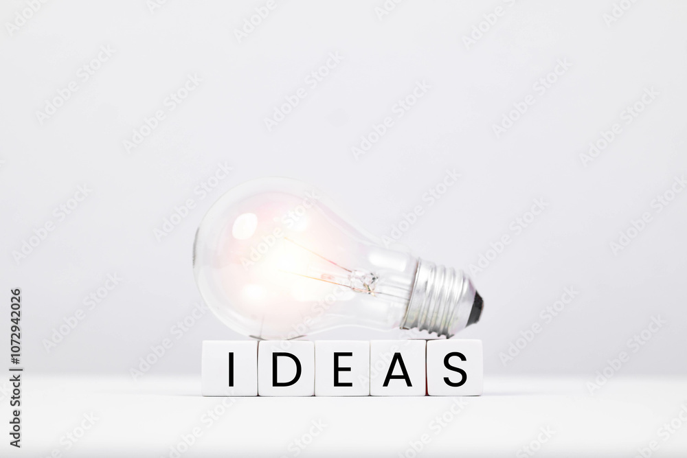 A glowing light bulb symbolizes creativity and innovation, positioned atop cubes that spell out the word 'IDEAS'. A glowing light bulb symbolizes creativity and innovation, positioned atop cubes that spell out the word 'IDEAS'.
