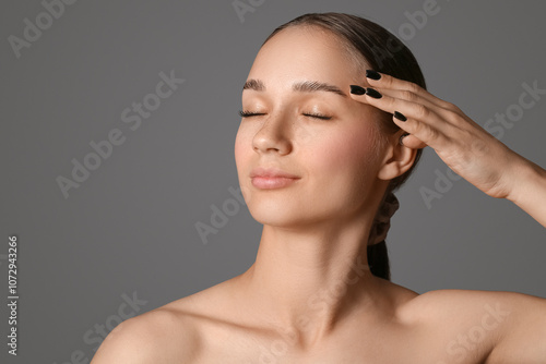 Young woman with beautiful eyebrows on grey background photo