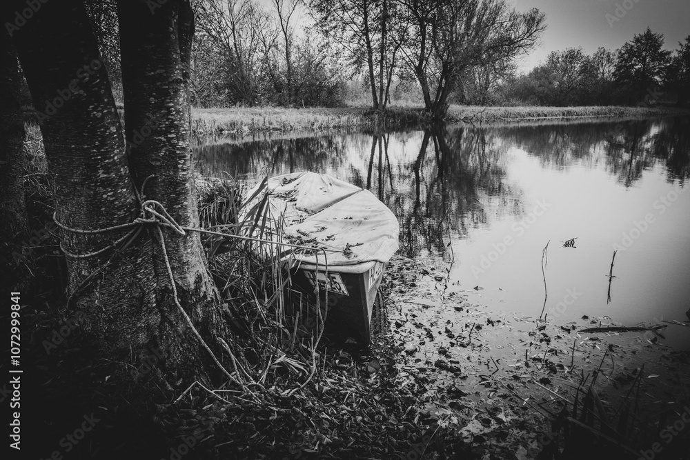 an old rowing boat lies on the shore of a lake in autumn