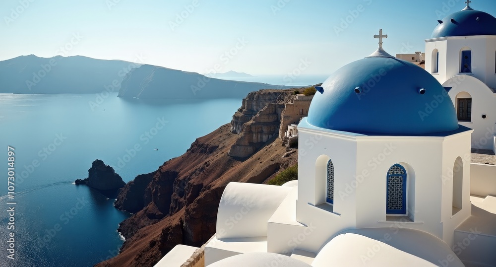 Fototapeta premium Whitewashed buildings and blue domes in Santorini, Greece, with Aegean Sea views under bright sunlight, capturing the iconic, serene Mediterranean charm.