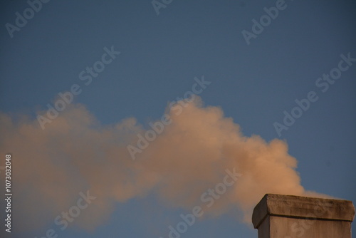 Thick white smoke from a stove pipe on a clear day