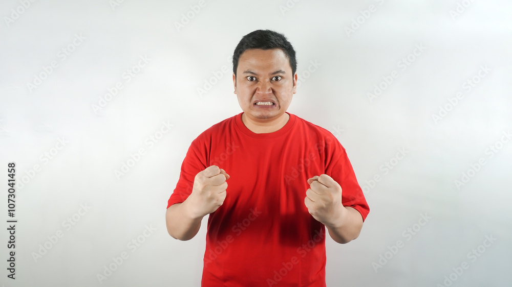 Naklejka premium A young Indonesian man wearing a red t-shirt with an angry face facing forward