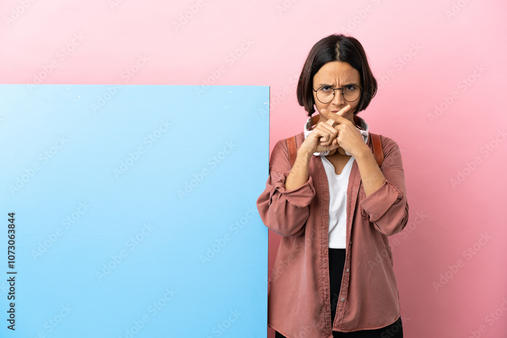 Young student mixed race woman with a big banner over isolated background showing a sign of silence gesture Young student mixed race woman with a big banner over isolated background showing a sign of silence gesture