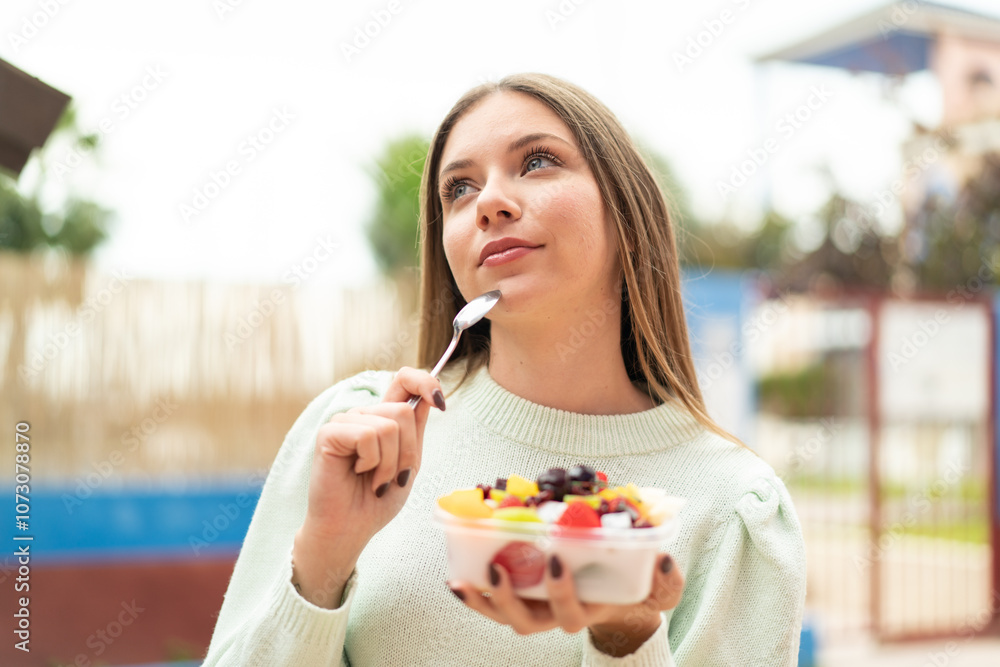 Young pretty blonde woman holding a bowl of fruit at outdoors Young pretty blonde woman holding a bowl of fruit at outdoors