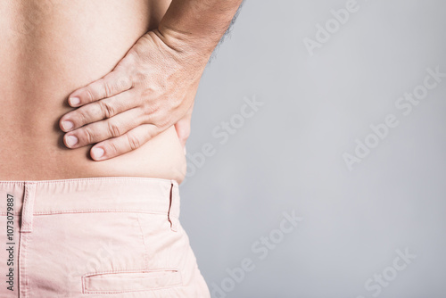 Man presses his hand against his waist, showing discomfort from muscle pain in the lower back and hips, potentially caused by excess weight. Effects of obesity on musculoskeletal health photo