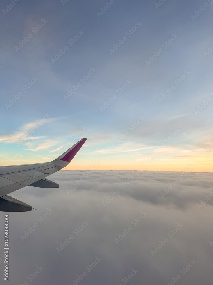 Obraz premium Sunset above clouds from a plane window, blue sky