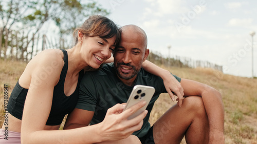 Close-up of athletic couple in love relaxing and using smartphone, front view