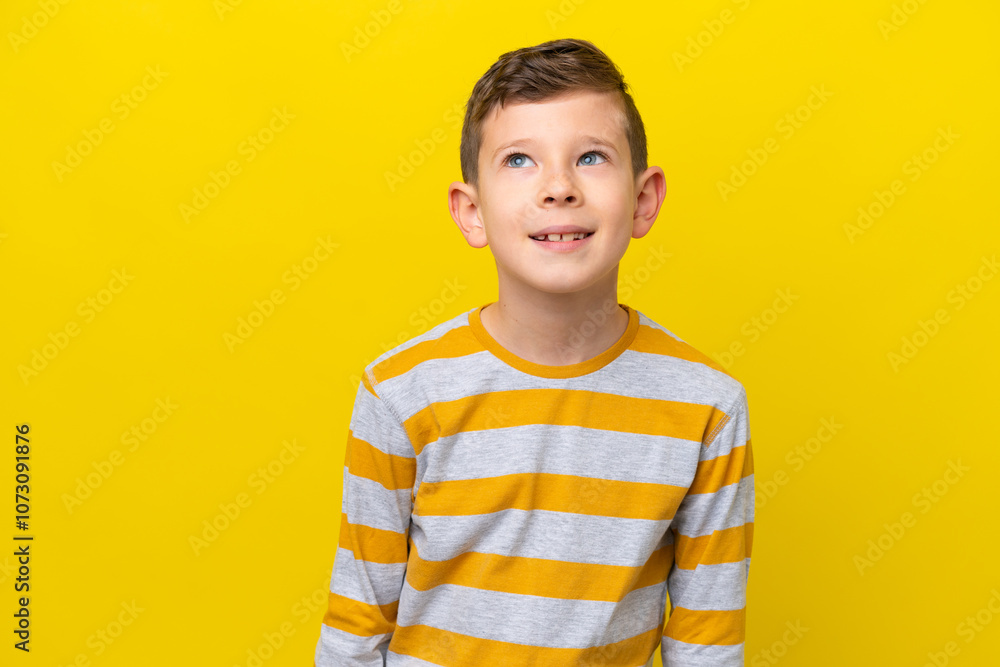 Little caucasian boy isolated on yellow background thinking an idea while looking up Little caucasian boy isolated on yellow background thinking an idea while looking up