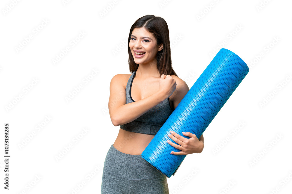 Young sport woman going to yoga classes while holding a mat over isolated chroma key background celebrating a victory Young sport woman going to yoga classes while holding a mat over isolated chroma key background celebrating a victory