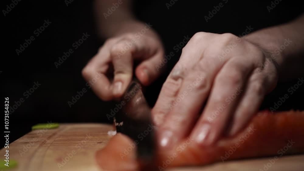 Close-Up of Hands Slicing Fresh Salmon Fillet on a Dark Background Close-Up of Hands Slicing Fresh Salmon Fillet on a Dark Background