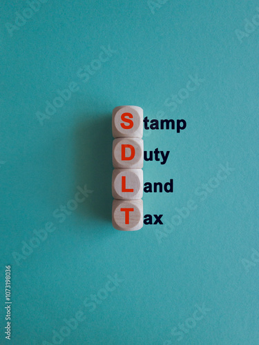 Wooden cubes with the word SDLT- Stamp duty Land Tax. Beautiful blue background. Business and buying housing and land concept. photo