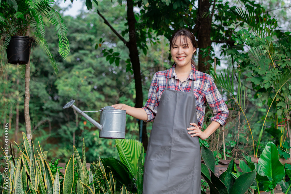 Asian woman watering plants in lush garden. Wearing apron and plaid shirt, surrounded by green foliage and potted plants. Smiling, enjoying weekend gardening outdoor activity, garden working in botany Asian woman watering plants in lush garden. Wearing apron and plaid shirt, surrounded by green foliage and potted plants. Smiling, enjoying weekend gardening outdoor activity, garden working in botany