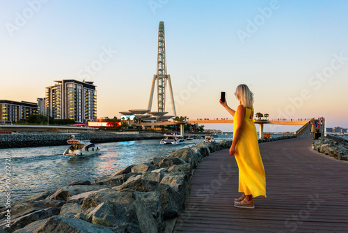 Photography Mature woman tourist in yellow dress in Dubai marina taking selfie