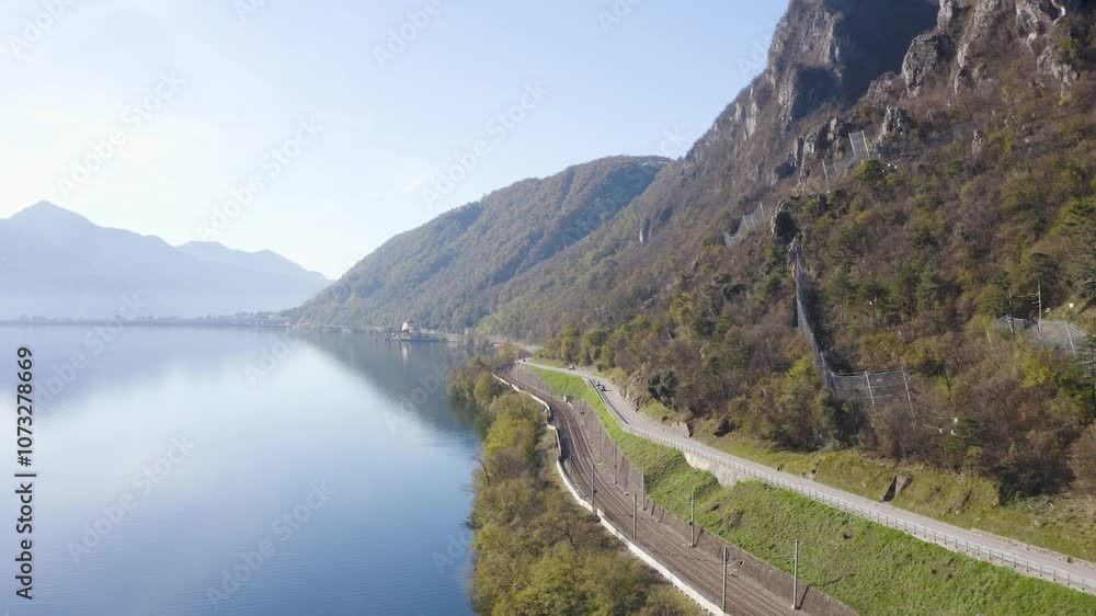 Drone flies over Lake Ceresio in Switzerland in the direction of Melide. On the right you can see the roadway and the railway. Drone flies over Lake Ceresio in Switzerland in the direction of Melide. On the right you can see the roadway and the railway.