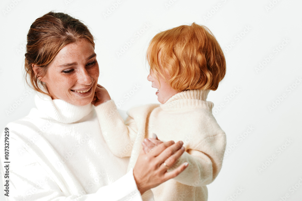 Mother and daughter embracing in white sweater on neutral background for family, love, and lifestyle concept Mother and daughter embracing in white sweater on neutral background for family, love, and lifestyle concept