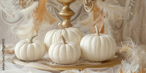 Elegant white pumpkins and feathers on a golden plate for autumn decor.