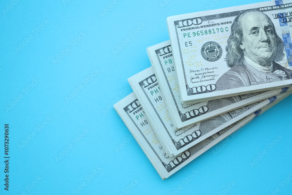 Big amount of hundred dollar bills in thick stack lies on bright blue color paper background Big amount of hundred dollar bills in thick stack lies on bright blue color paper background