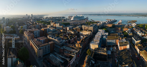 Obraz na płótnie Southampton UK seaside city panorama. Wide angle aerial view from the ferry terminal and port with large cruise ship mooring towards the Itchen toll bridge. Beautiful sunrise and calm sea. Urban area. w salonie