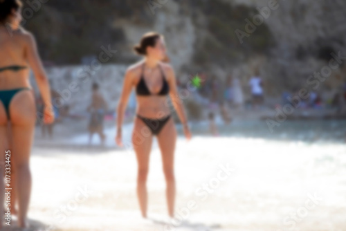 Summer vacation, silhouettes of women playing on the beach. Defocused, blurred image of beach