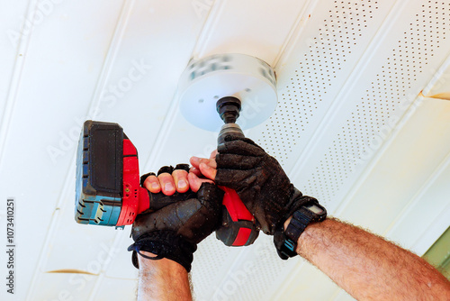 Billede på lærred An individual wearing gloves holds cordless drill that has hole saw attachment a