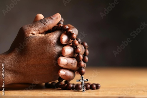 Man's hands pray to hold a bead rosary with Jesus Christ on the cross or the Crucifix. Christian Catholic religious faith holding a black rosary and praying.

